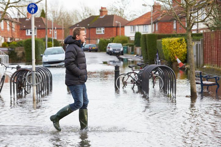 Man Walking Along Flooded Urban Street