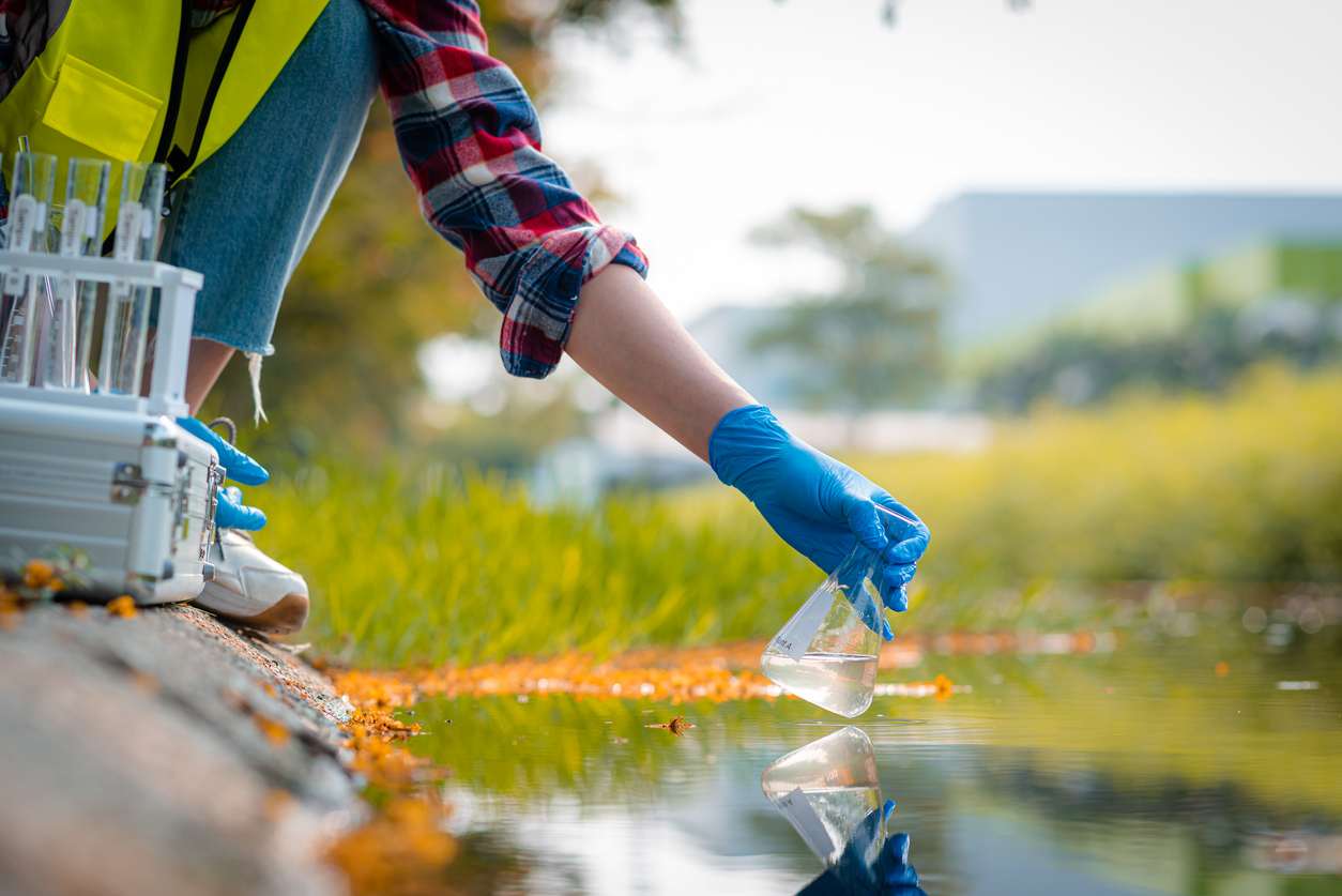 Hands of scientists collecting water samples for analysis and research on water quality.