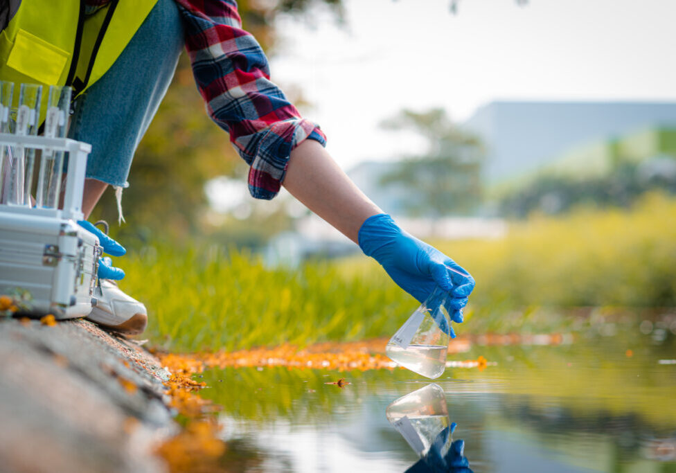 Hands of scientists collecting water samples for analysis and research on water quality.
